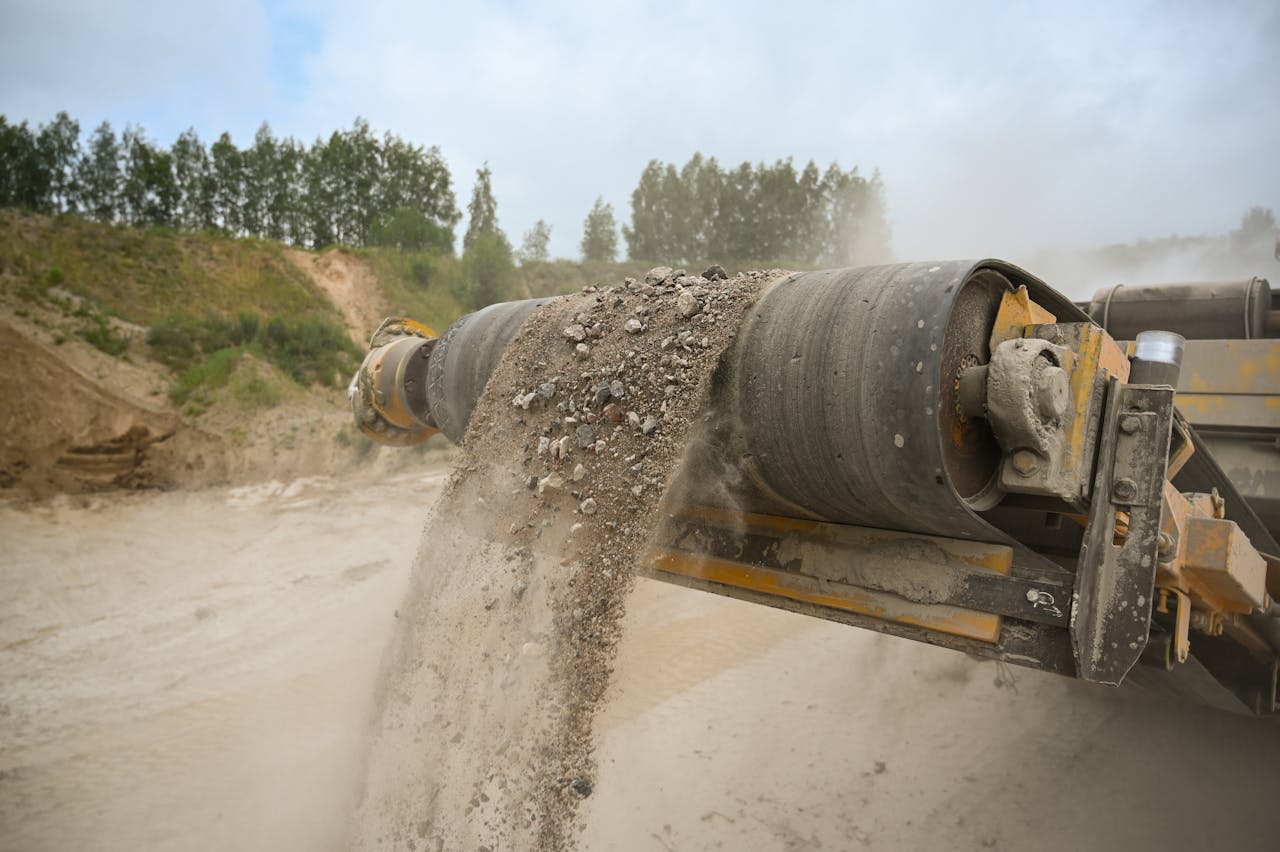hero-img-02 A close-up of an industrial conveyor belt moving gravel at a construction site